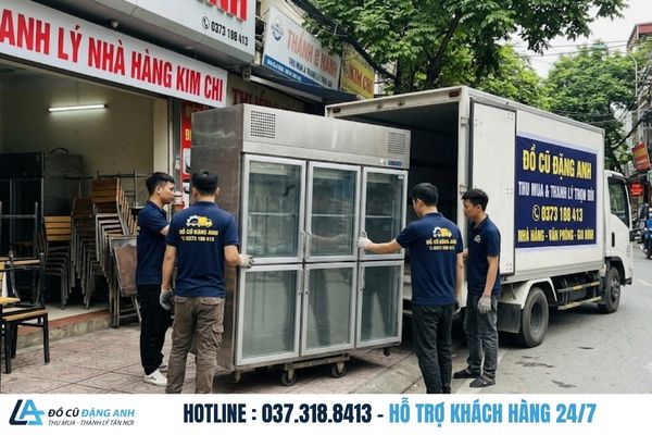 Đội ngũ Đồ Cũ Đặng Anh mặc đồng phục xanh đậm đang di chuyển tủ đông ra ngoài