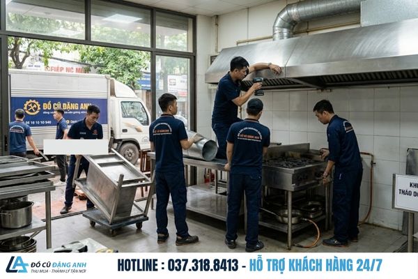 Đội ngũ Đồ Cũ Đặng Anh mặc đồng phục xanh đậm đang tháo bếp và bàn inox