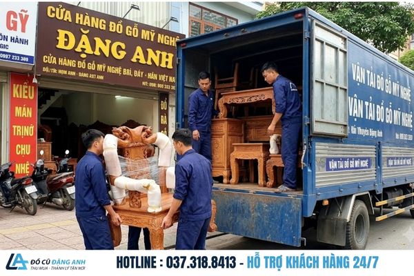 Đội ngũ nhân viên mặc đồng phục xanh đậm đang cẩn thận bốc xếp bàn ghế đồ gỗ mỹ nghệ lên xe tải