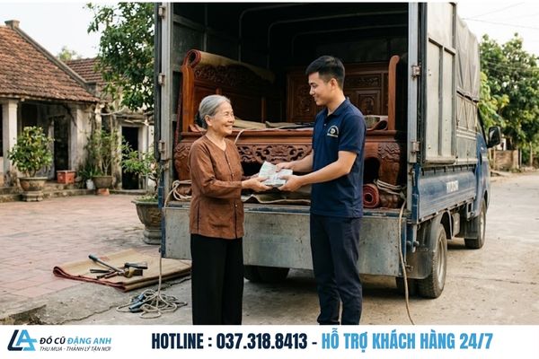 Khách hàng bà cụ hài lòng nhận thanh toán tiền mặt 100% từ nhân viên mặc đồng phục xanh đậm sau khi hoàn tất bốc xếp sập gụ tủ chè lên xe