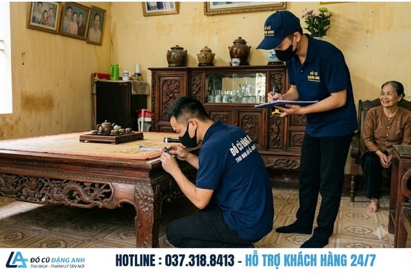 Thợ của Đồ Cũ Đặng Anh mặc đồng phục xanh đậm đang khảo sát và định giá bộ sập gụ tủ chè tại nhà khách - thu mua đồ gỗ cũ tại hà nội